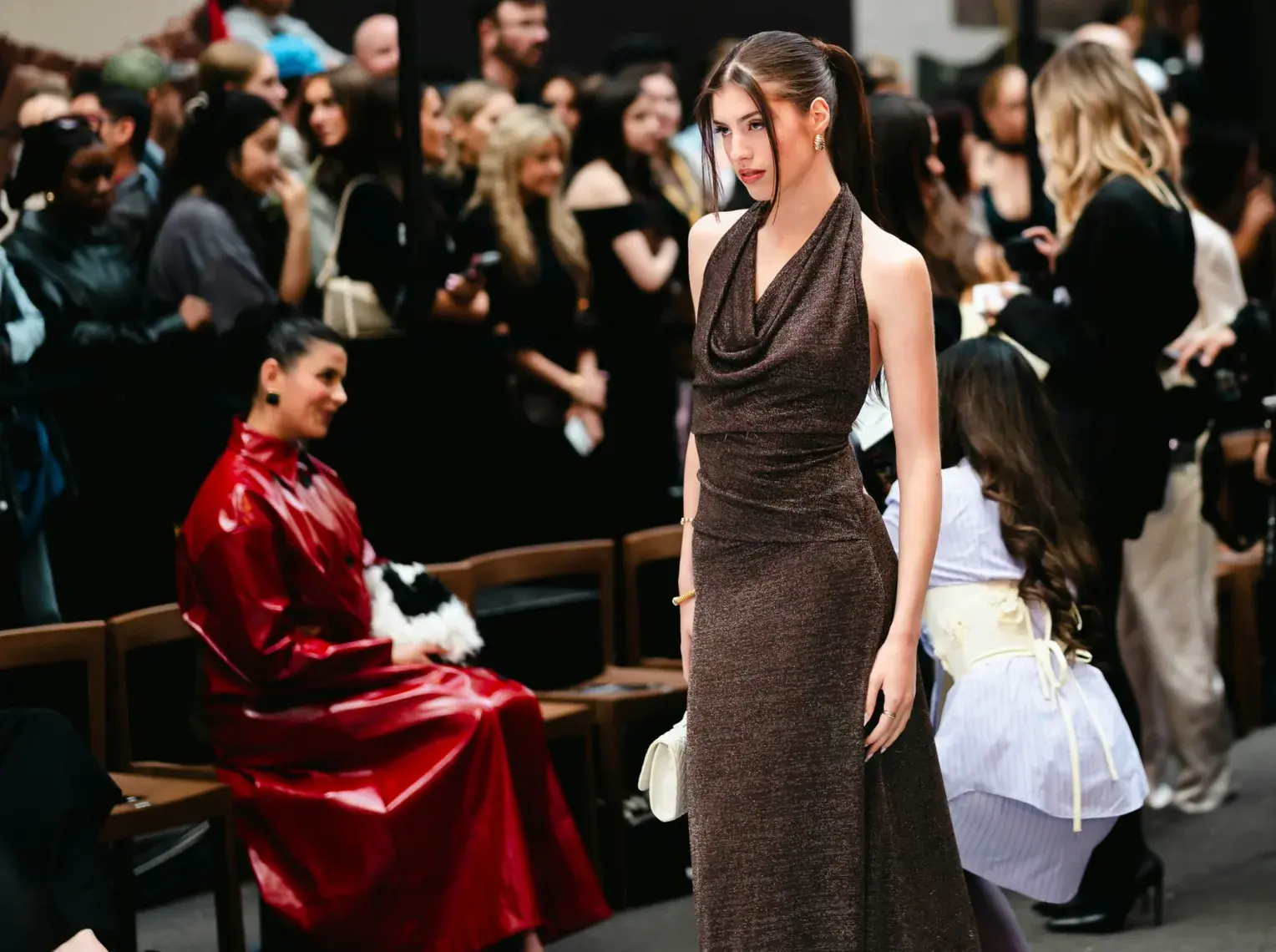 Luxury and Fashion - Model walking a fashion-show runway, with a seated front-row audience behind her.