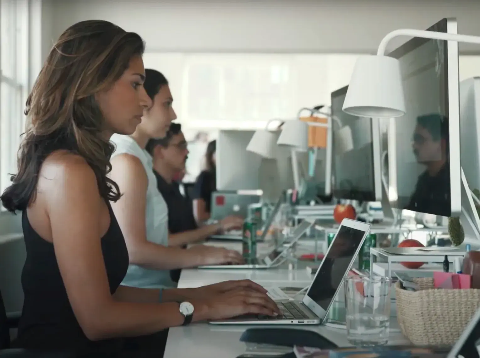 PR and Communications Agencies — Colleagues working on laptops along a bright shared office desk